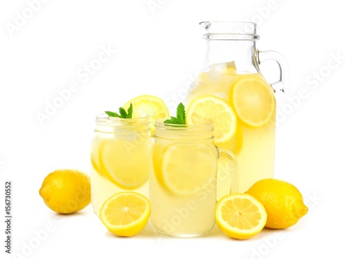 Vintage pitcher of lemonade with two mason jar glasses and lemons isolated on a white background