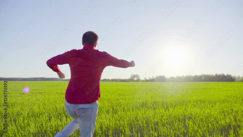 Successful businessman running and jumping on a green wheat field, slow motion Successful businessman running and jumping on a green wheat field, slow motion