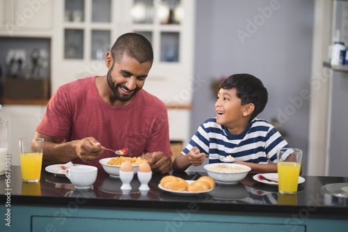 Happy man with his son having breakfast in kitchen