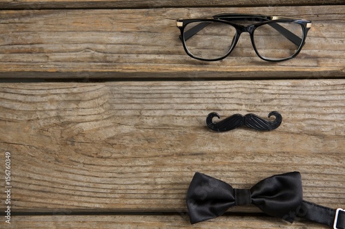 High angle view of mustache with eyeglasses and bow tie on table