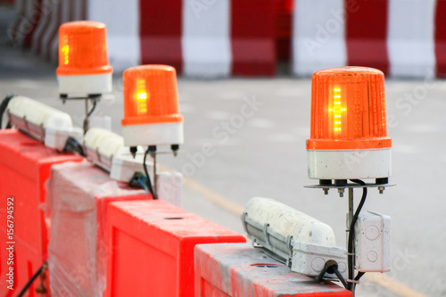 Orange flashing and revolving light on top of fence, Sirens with blurred background , message under construction.