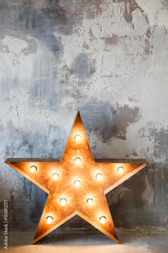 metal star with lamps near gray plaster wall in studio