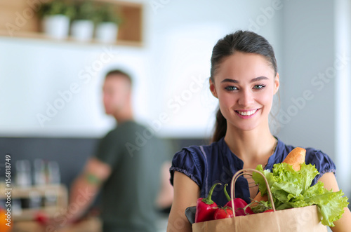 Young couple in the kitchen , woman with a bag of groceries shopping photo