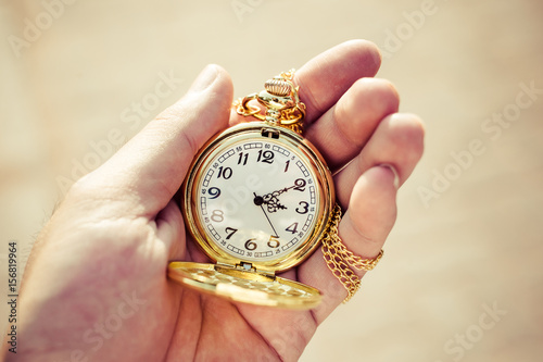 Golden pocket watch in hand close up.