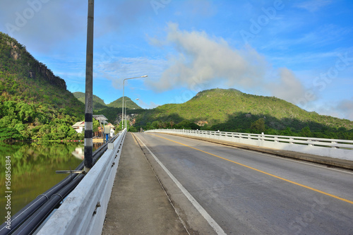 .Bridge heading to mountains with blue sky background in Thailand.