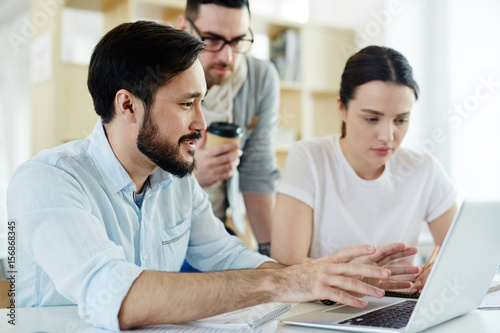 Portrait of business team working with laptop in modern office, collaborating on project strategy