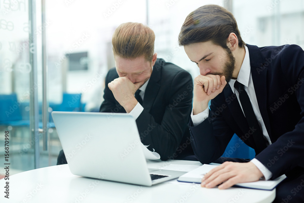 Stressed businessmen sitting by workplace in front of laptop Stressed businessmen sitting by workplace in front of laptop