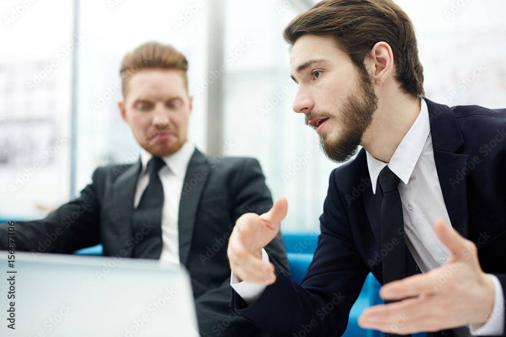 Salesman explaining his idea of overcoming crisis to co-worker Salesman explaining his idea of overcoming crisis to co-worker
