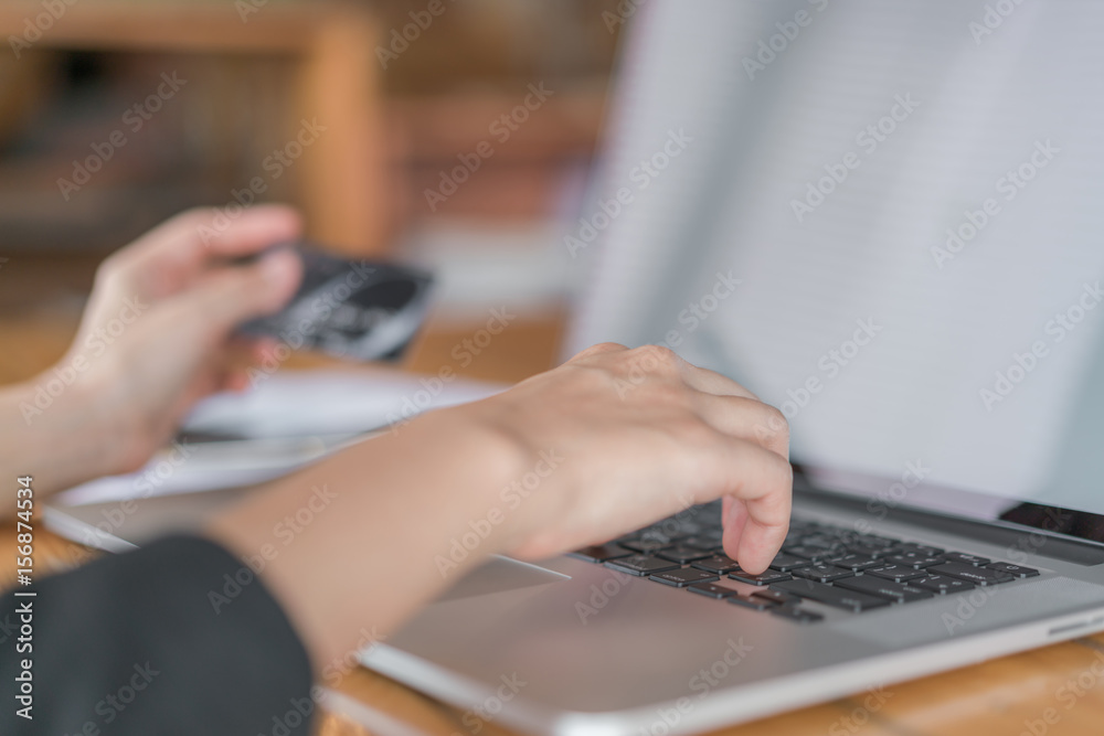 Hands holding a credit card and using laptop computer for online shopping .