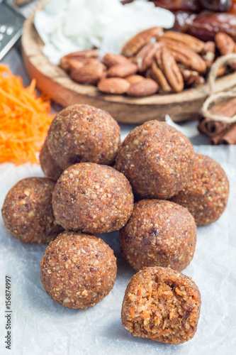 Healthy homemade paleo energy balls with carrot, nuts, dates and coconut flakes, on parchment, vertical