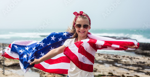 American flag. Little smiling  patriotic girl with long blond hair holding American flag on Independence day USA, July 4th. Memorial day