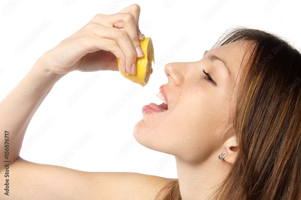 profile of a young attractive woman pouring lemon juice in her mouth from a slice of lemon she squeezes in her hand. studio portrait isolated on white background profile of a young attractive woman pouring lemon juice in her mouth from a slice of lemon she squeezes in her hand. studio portrait isolated on white background