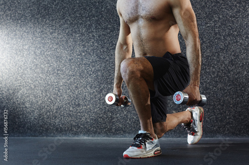 Shirtless man exercising with dumbbells on the floor