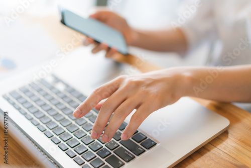 Business woman hand with Financial charts and mobile phone over laptop on the table .