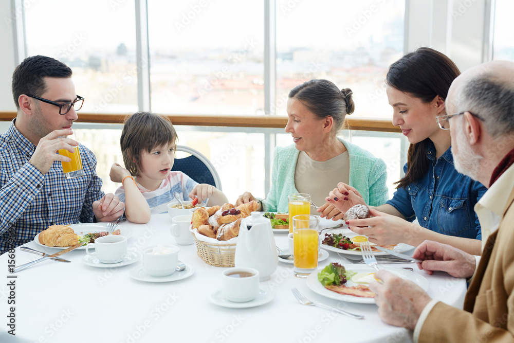 Three generations sitting in hotel cafe and talking by breakfast Three generations sitting in hotel cafe and talking by breakfast