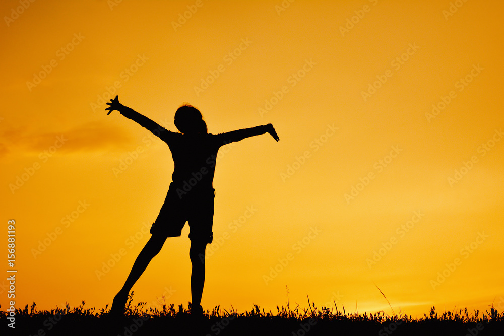Silhouette of happy girl standing on grass field and sky sunset Silhouette of happy girl standing on grass field and sky sunset