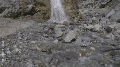 Steadicam through a river to a Massive Waterfall in the Mountains photo