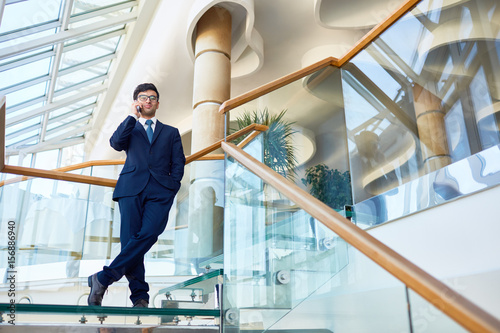 Confident employer speaking on cellphone in modern building