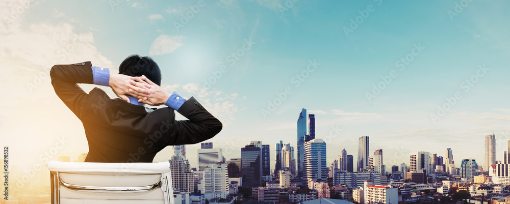 Businessman stretching arm for relax with cityscape view in sunrise, panoramic for web banner Businessman stretching arm for relax with cityscape view in sunrise, panoramic for web banner