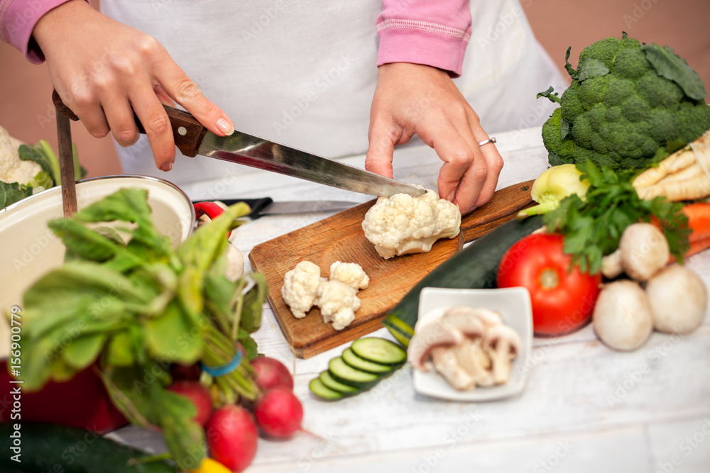 Woman cutting cauliflower with a knife Woman cutting cauliflower with a knife