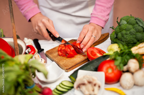 Fototapeta Naklejka Na Ścianę i Meble -  Woman cutting tomato on slices on chopping board