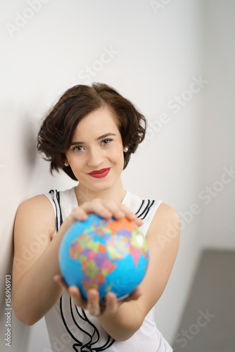 selbstbewusste junge frau hält einen globus in den händen