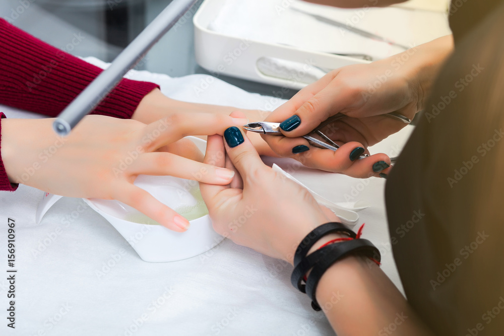 Fototapeta premium Hands of the girl in the baths with water during a manicure, cleansing the cuticle