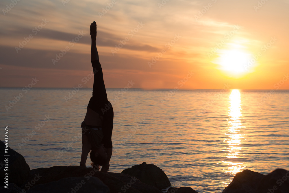 fitness mixed race asian woman in yoga pose on the morning beach, beautiful fit woman practice fitness exrxise stones, morning sea or ocean background