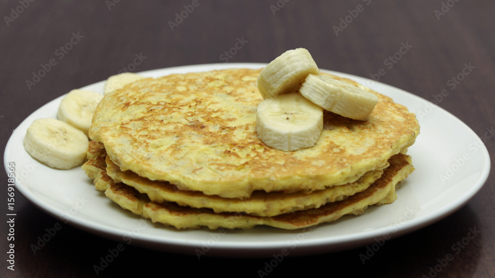 Healthy Pancakes with Banana Slices on White Plate on Wooden Table