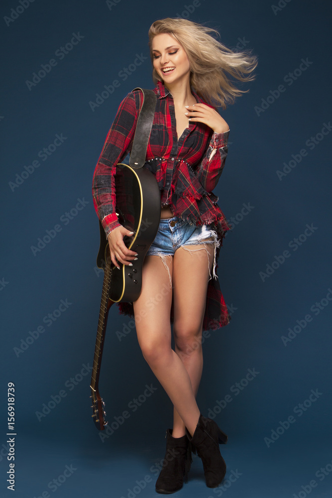 Young beautiful blond girl playing on guitar. Concert. Hobby. Rock and roll. Young beautiful blond girl playing on guitar. Concert. Hobby. Rock and roll.