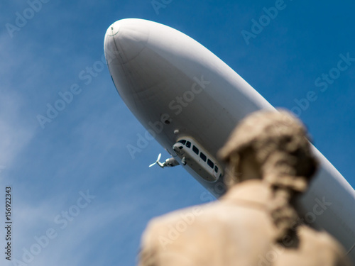 White Zeppelin Aircraft with statue in foreground
