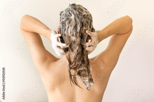 Attractive model shampooing her long hair from behind.