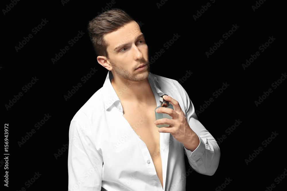 Handsome man using perfume on black background Handsome man using perfume on black background