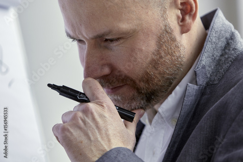 Businessman Holding a Marker and Looking at the Board photo