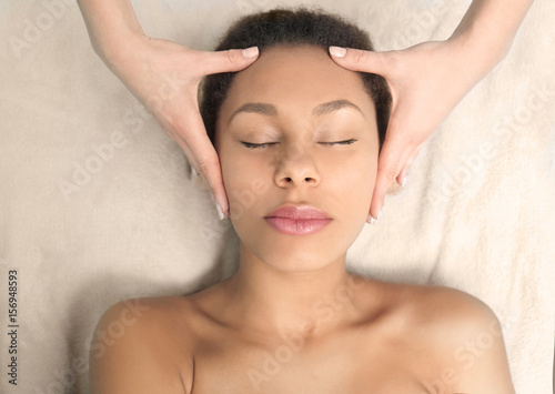 Beautiful African-American girl having massage in spa salon