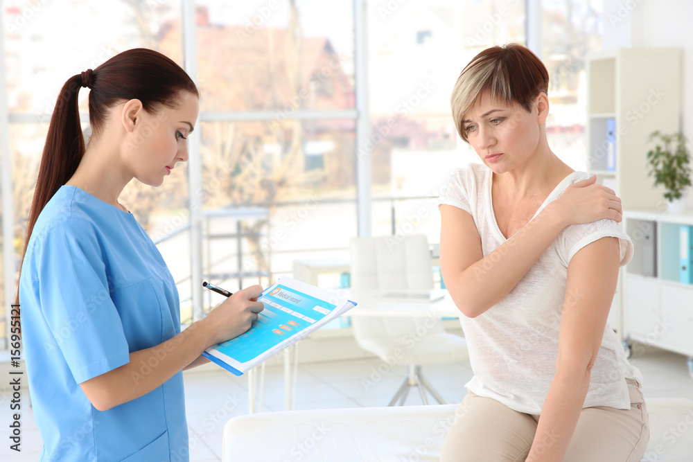 Orthopedist examining middle-aged woman in clinic Orthopedist examining middle-aged woman in clinic