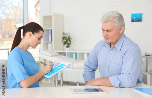 Female orthopedist examining senior man in clinic