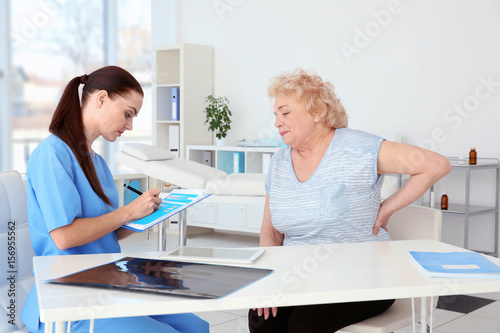 Female orthopedist examining senior woman in clinic