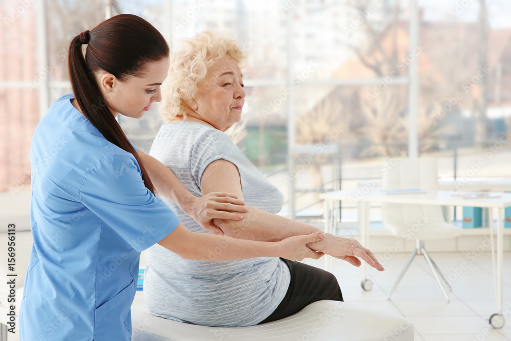 Female orthopedist examining senior woman in clinic Female orthopedist examining senior woman in clinic