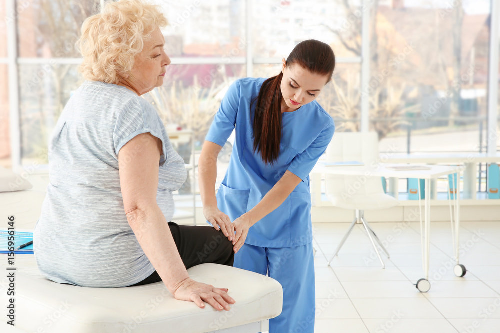 Fototapeta premium Female orthopedist examining senior woman in clinic