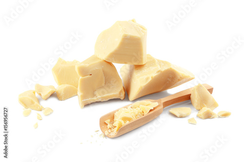 Wooden scoop and pieces of cocoa butter on white background
