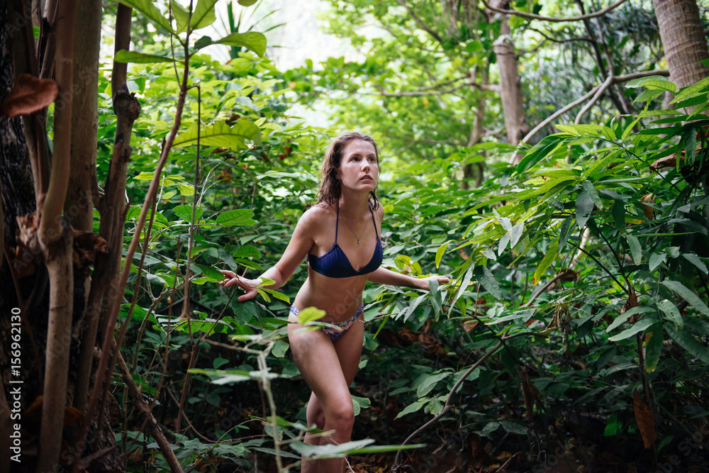 Young beautiful girl in bikini walking in tropical forest. Traveler lost in  the jungle forest Stock Photo | Adobe Stock