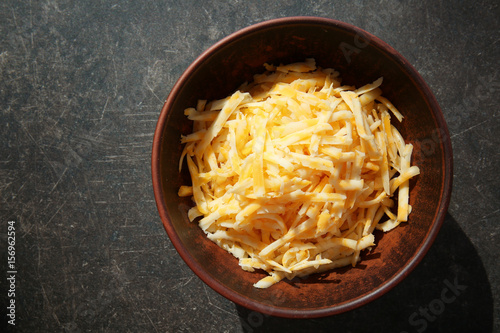 Bowl with delicious cheese on dark background