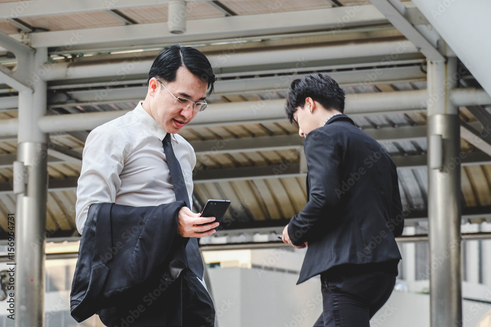 Businessman holding and looking smartphone, man walk past
