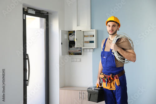 Young electrician with bunch of wires indoors