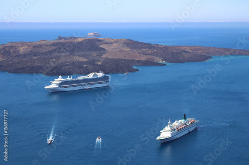 Zwei Kreuzfahrtschiffe ankern im blauen Meer im Krater des erloschen Vulkans von Santorin.