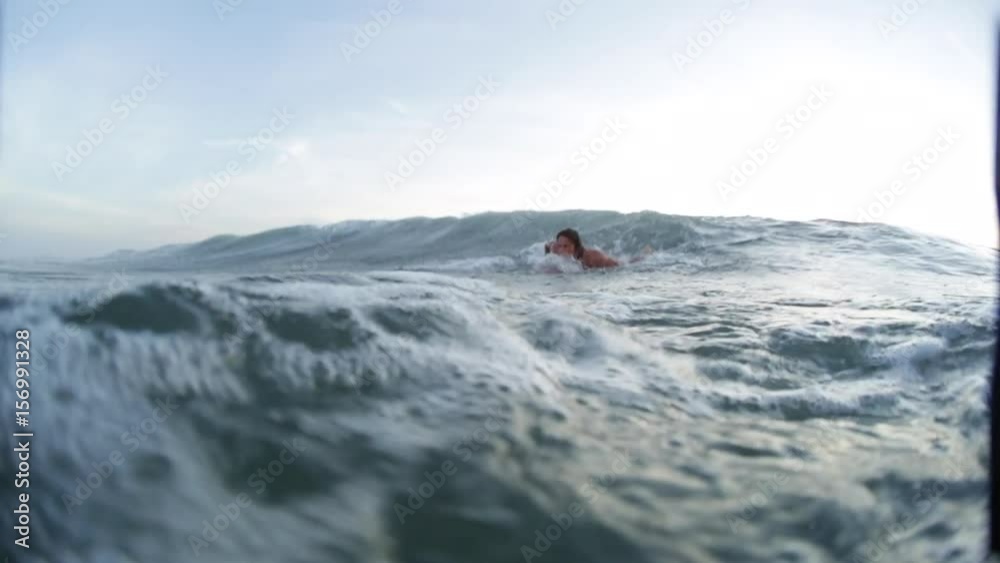 Young man with surf board moves through shorebreak to line up Young man with surf board moves through shorebreak to line up