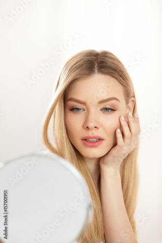 Makeup And Beauty. Female Touching Face Skin Looking In Mirror