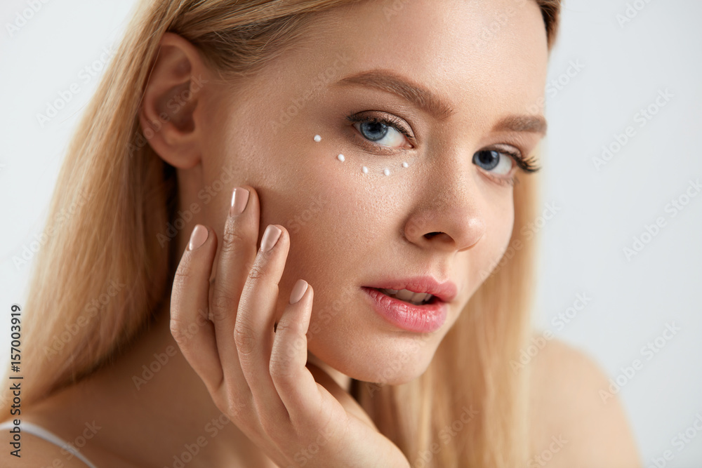 Facial Care. Woman With Drops Of Cosmetic Cream Under Eye