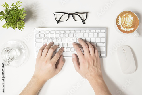 Hipster man is typing on computer keyboard, top view.
